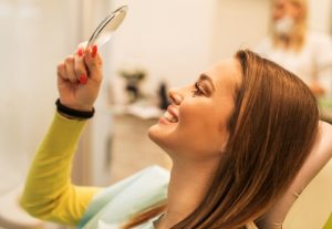 Woman in dental chair looking in a mirror at her teeth and gums