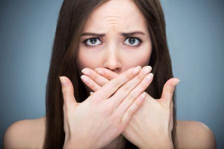 Woman covering her mouth from a dental emergency.