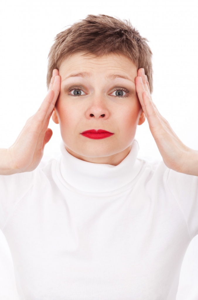 Woman holder her head in pain over a white background