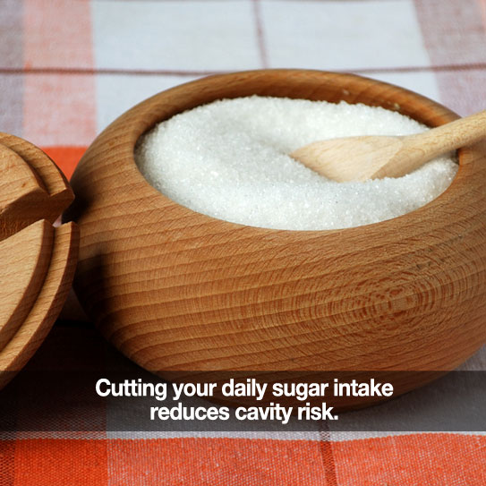 A container a sugar. Caption: Cutting your daily sugar intake reduces cavity risk.