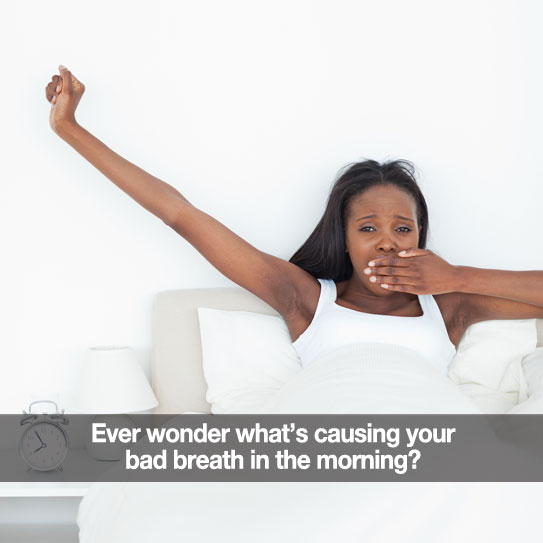 Woman waking up in bed stretching and covering her mouth as she yawns.