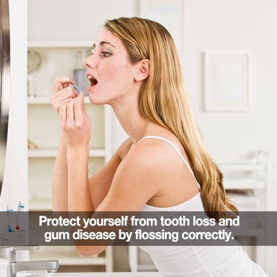 Woman flossing in front of her bathroom mirror