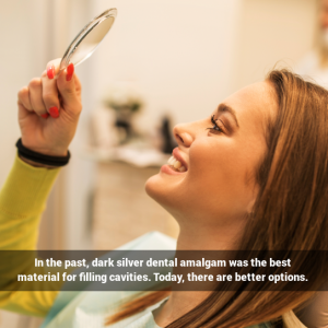 Woman in dental chair smiling in hand mirror
