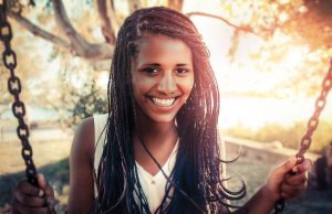 Smiling woman sitting on a swing during sunset.