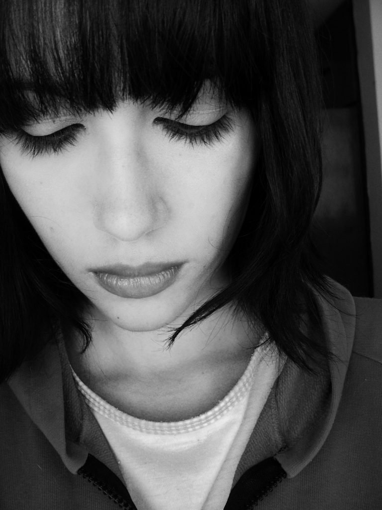 Black and white picture of a woman looking down and depressed