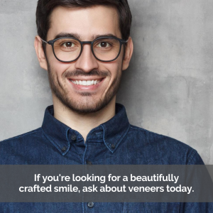 Man smiling about veneers in front of gray backdrop.