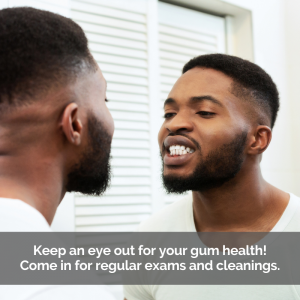 Looking for gum disease, a young man examines his gums in the mirror.