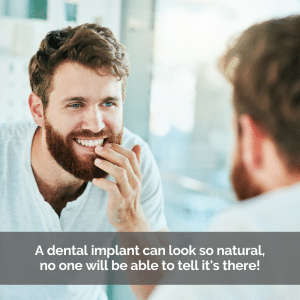 A man looking at his dental implants in the mirror.