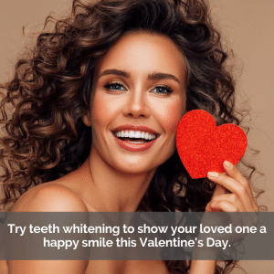 Beautiful woman with white teeth smiling while holding up a paper heart.