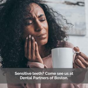 Sensitive teeth cause a woman to hold her cheek in pain while drinking coffee.