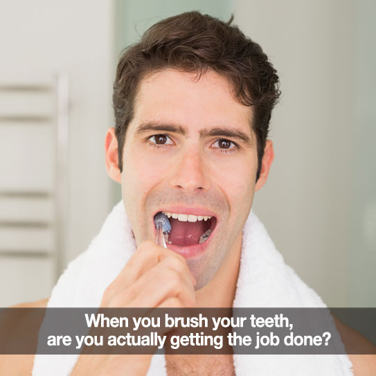 Man brushing his teeth with towel around his shoulders