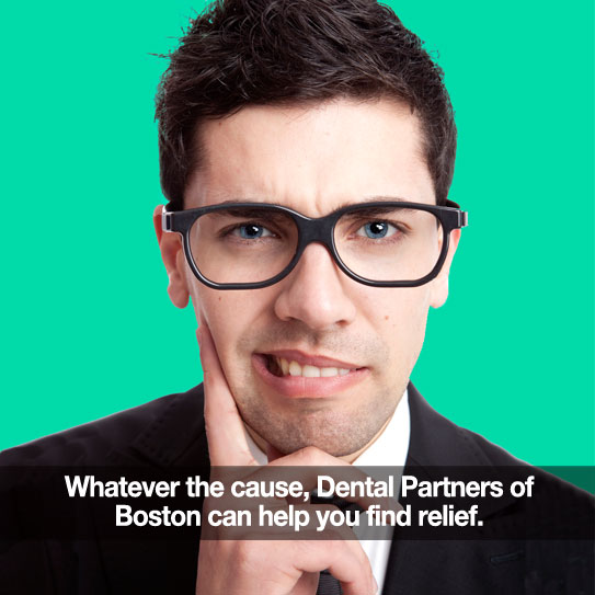 Man with glasses on green background holding his jaw in pain.
