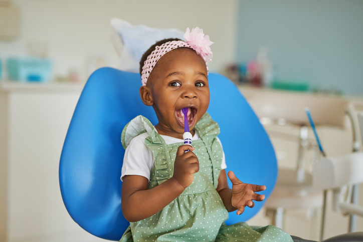 cute toddler girl with a toothbrush in dental chair
