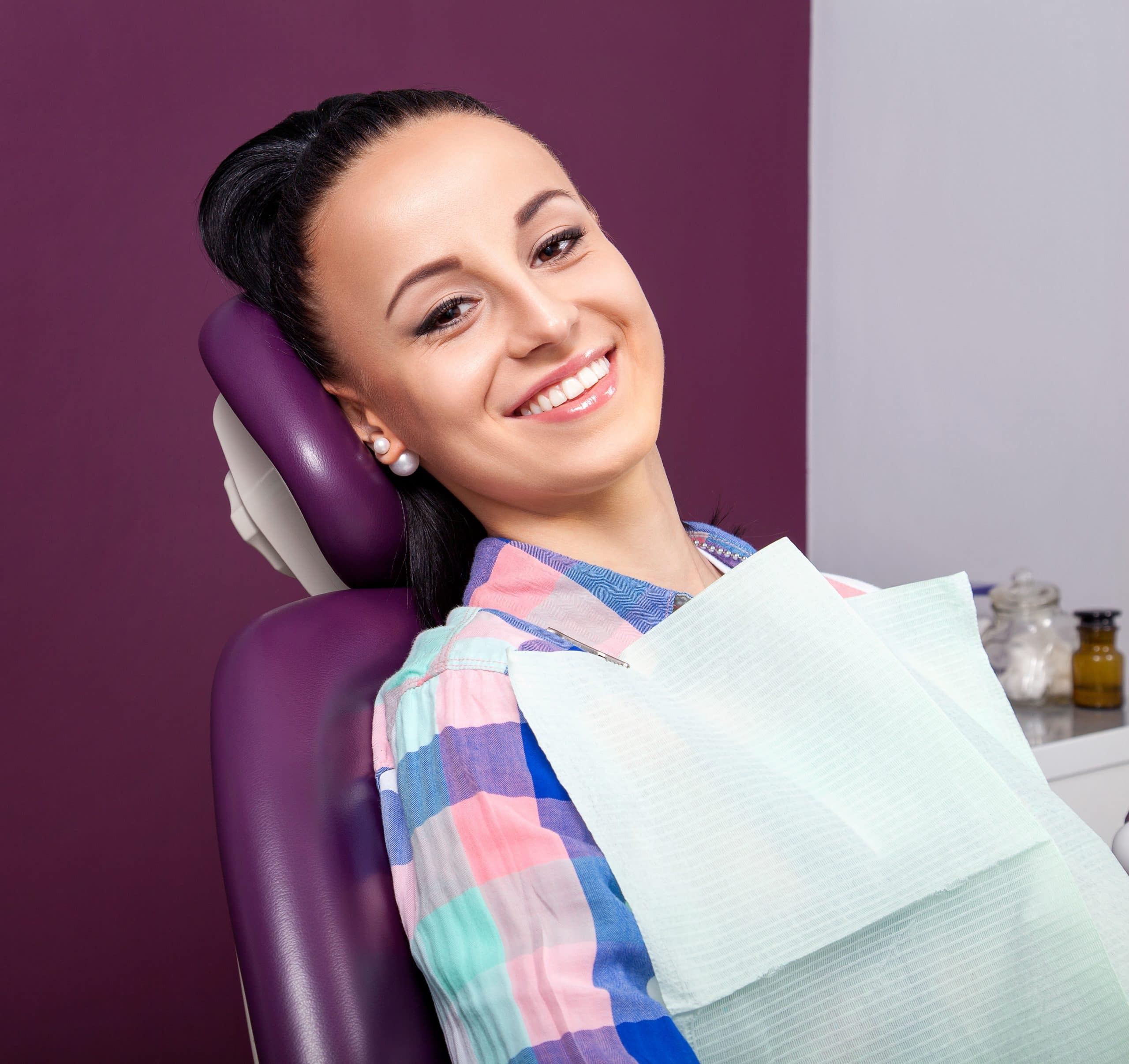 Woman in dental chair smiling purple background