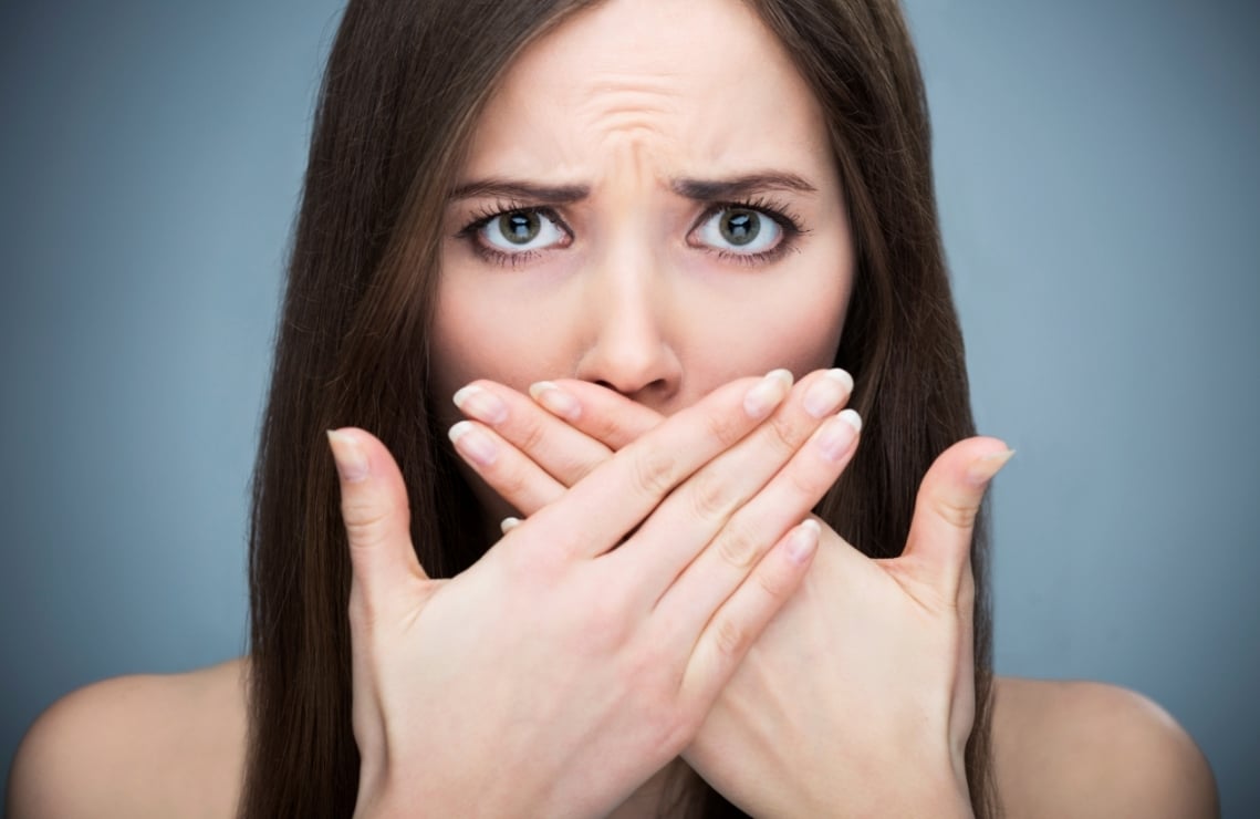 Woman with bad breath covering her mouth