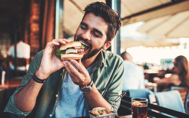 man with a dental implant sitting and enjoying eating lunch