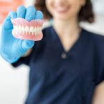 female dental hygienist holding dentures