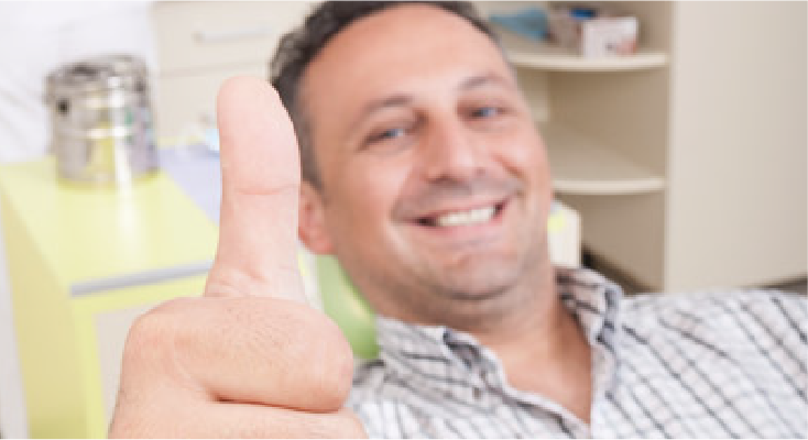 Man in a dental chair giving a thumb up