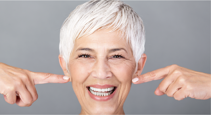 older woman smiling and pointing at her teeth