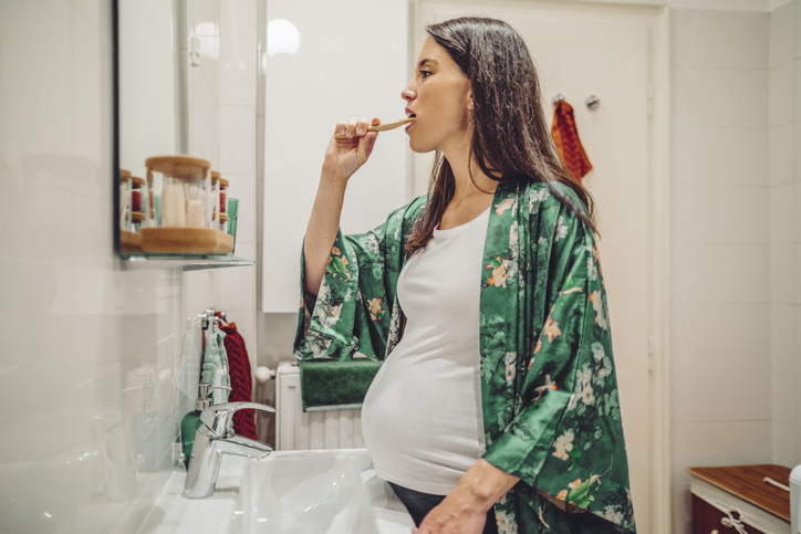 pregnant woman brushing her teeth