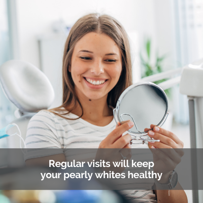 Woman smiling while looking in a mirror at the dentist office