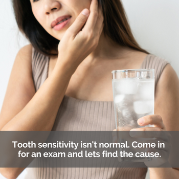 Woman holding her cheek and a glass of ice water.