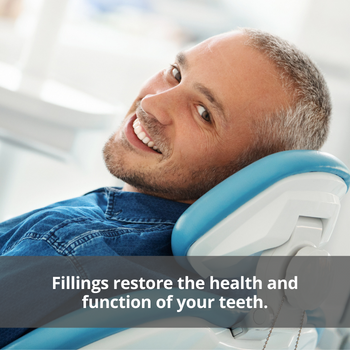 Man sitting in a dental chair smiling. Caption: Fillings restore the health and function of your teeth.