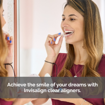 Woman looking in a mirror while putting an Invisalign aligner in her mouth