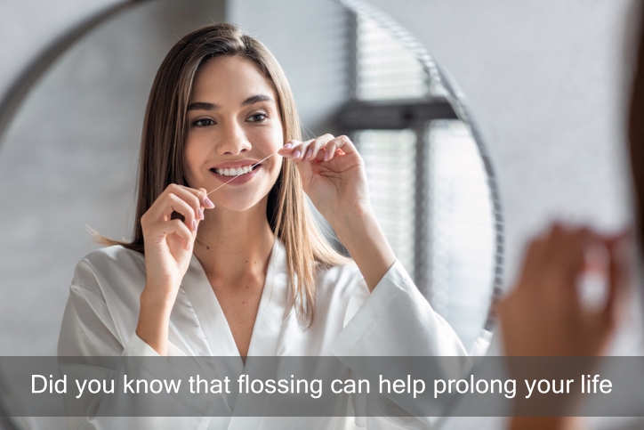 Attractive woman flossing her teeth in front of bathroom mirror