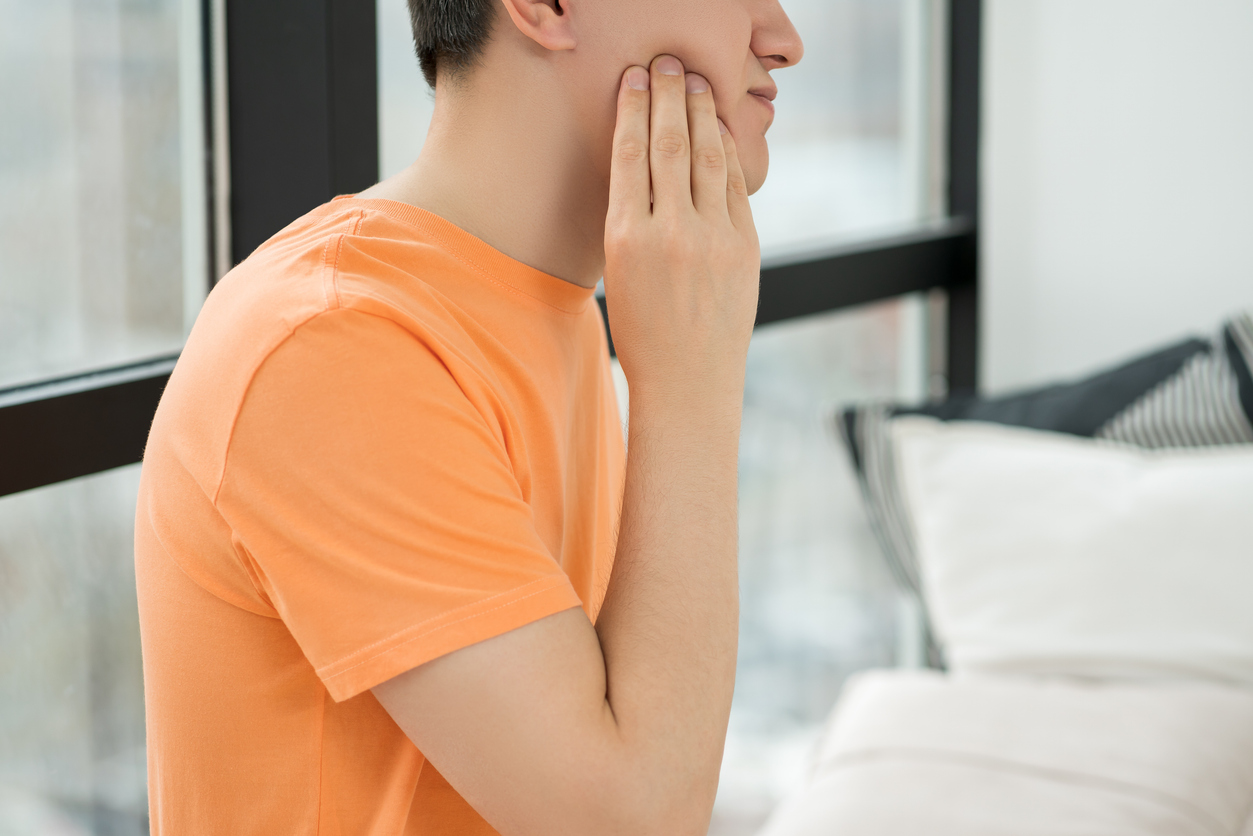 Man holding his jaw due to impacted wisdom tooth