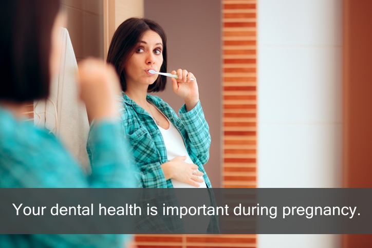 Pregnant woman brush her teeth in front of a mirror.