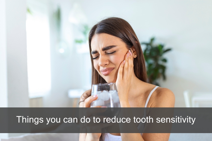 Woman in pain with sensitive teeth drinking ice water.