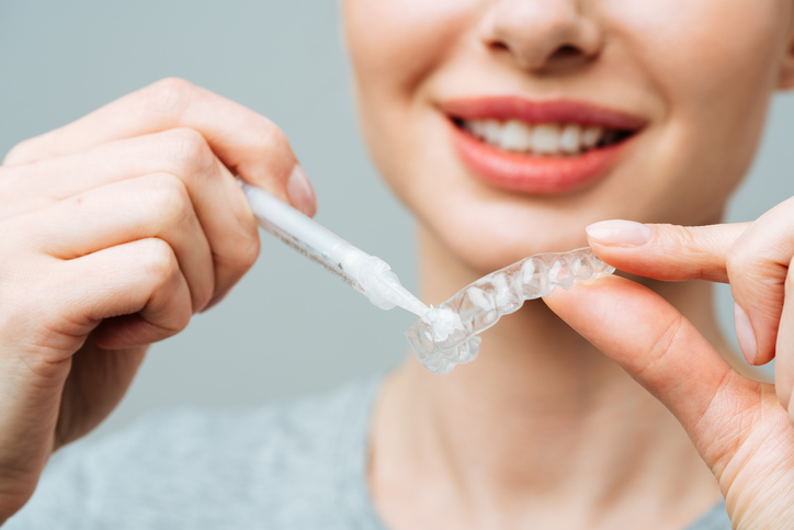 woman filling at-home teeth whitening trays 