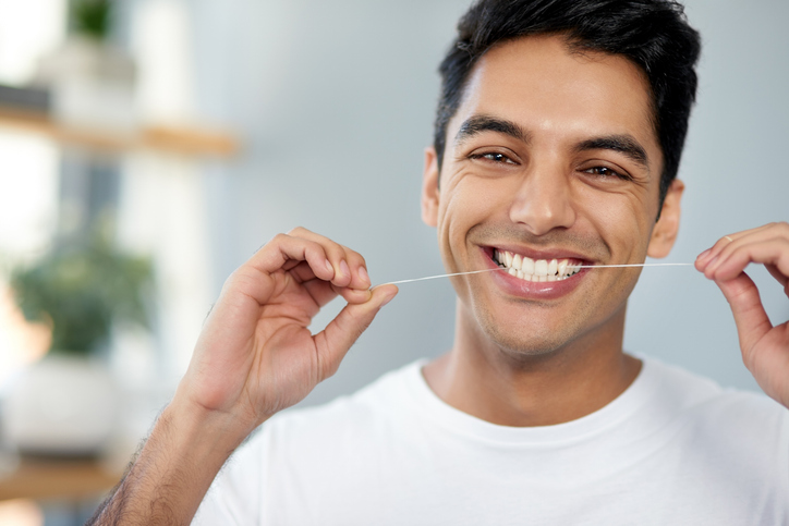 young man flossing his teeth at home