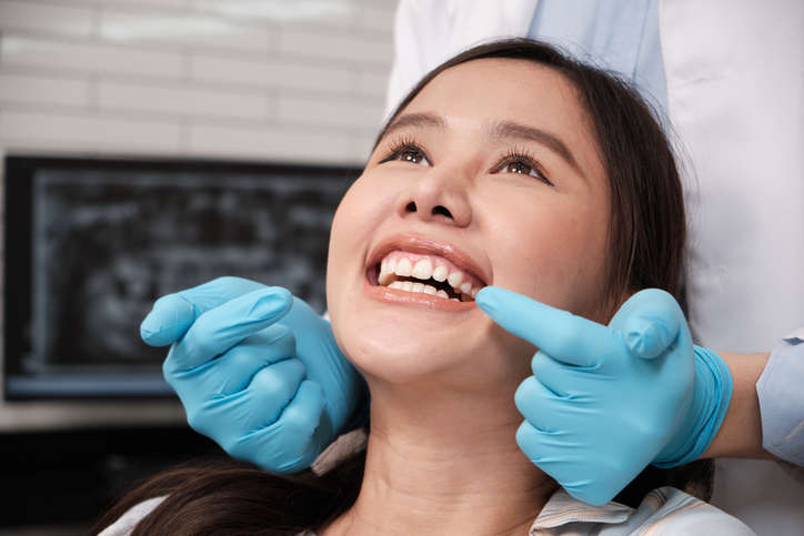 female dental patient smiling while dentist points at her teeth