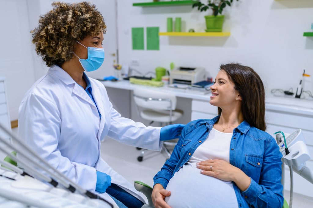 a pregnant woman visits with the dentist in the dental office