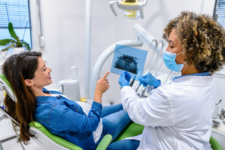 pregnant woman is shown her digital dental X-rays by a female dentist
