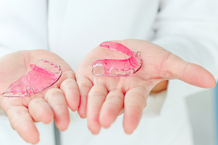 a dentist holding wired Hawley retainers.