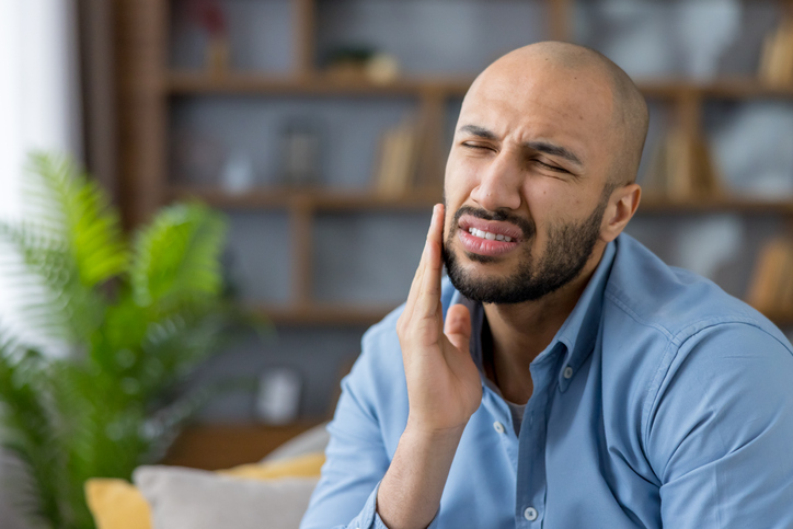 man with tooth pain at home holding his cheek